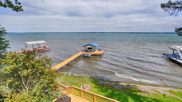 A lakeside dock with a covered seating area and a small boat. - Sunrise Shores: Spectacular View! (Penn Yan)