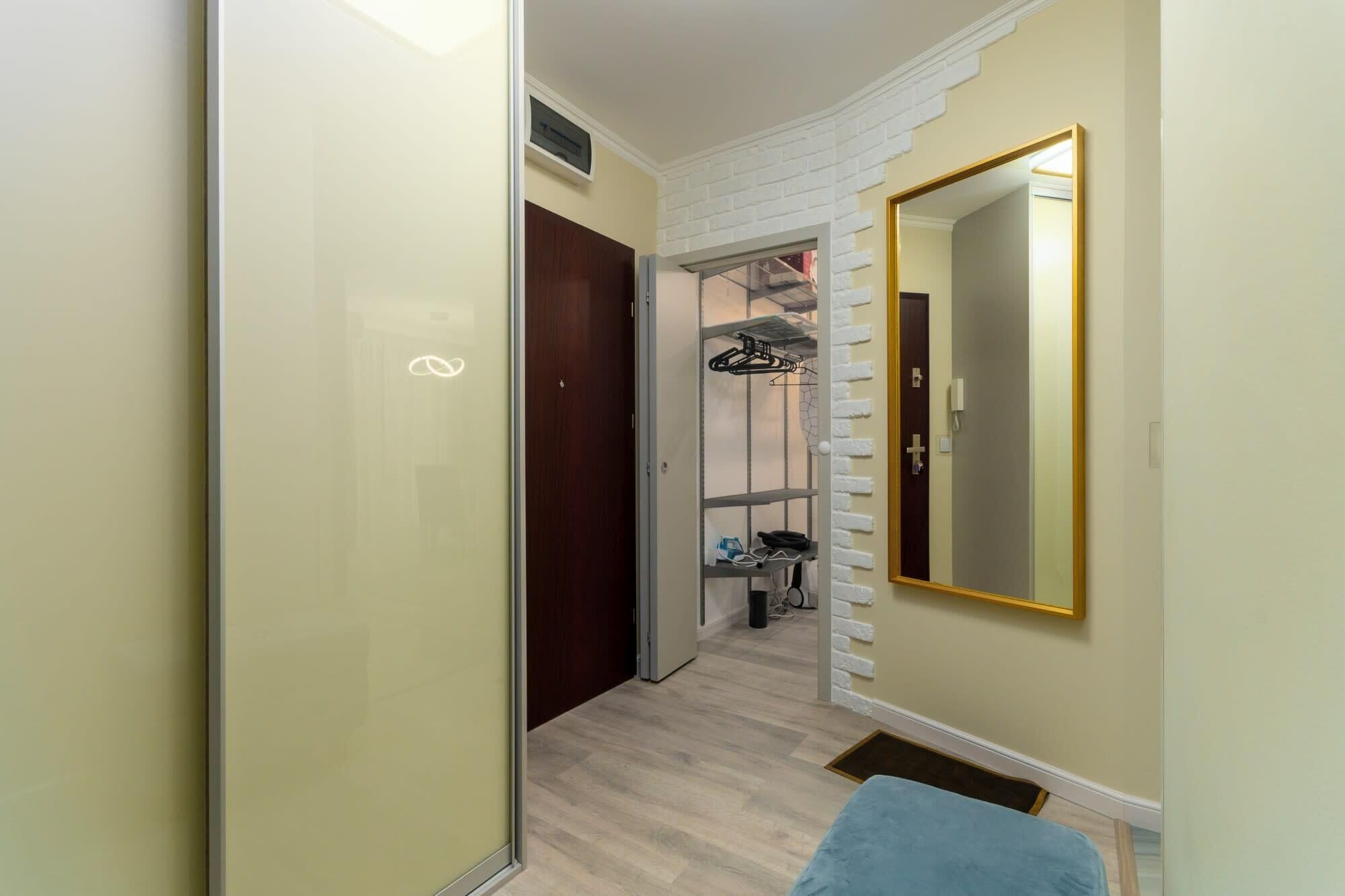 A hallway with a mirrored wardrobe, a coat rack, and a small seating area.