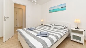 Une chambre à coucher avec un lit, des tables de chevet, un tableau et un lustre.