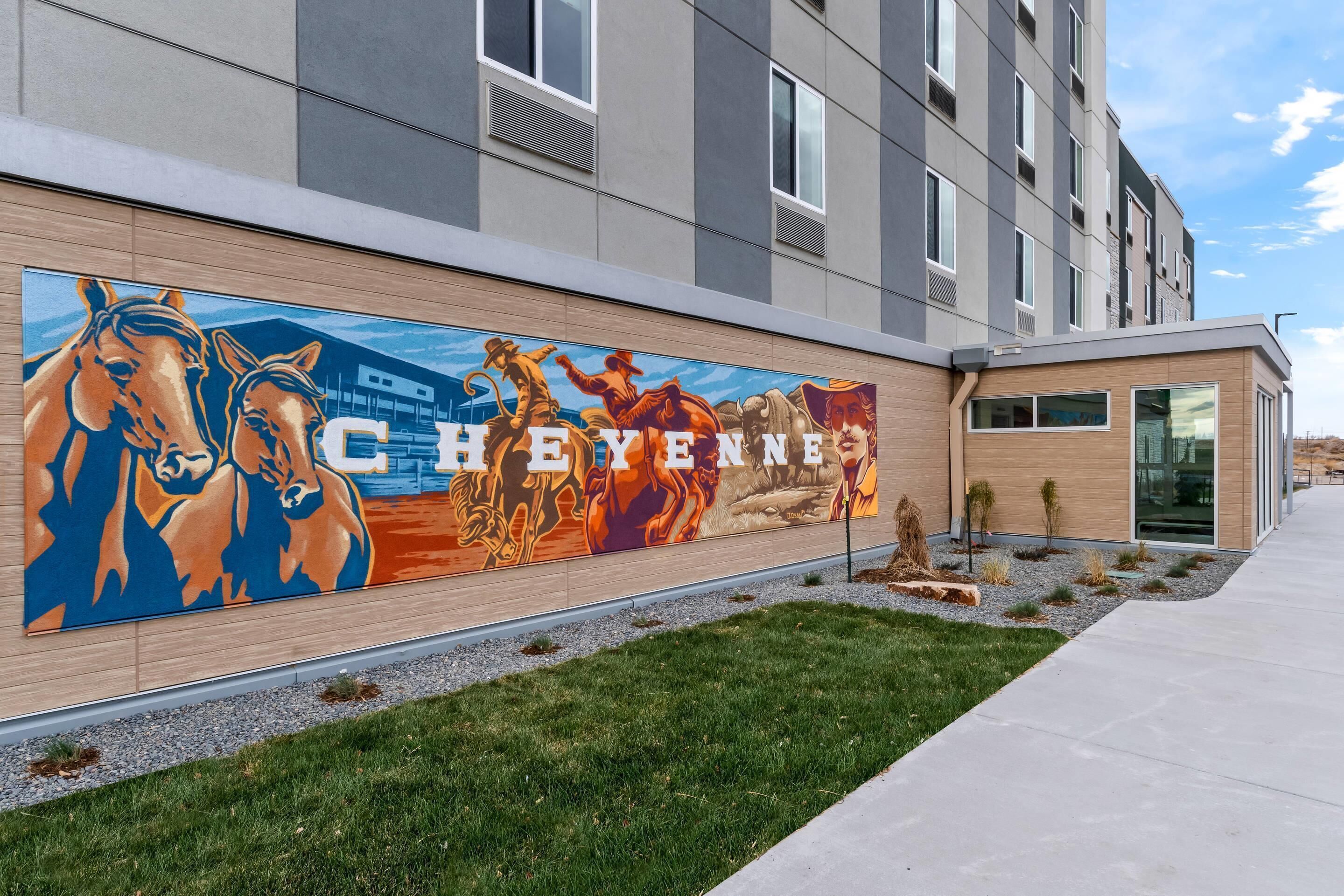 La façade d’un bâtiment est ornée d’une fresque représentant des chevaux, et le mot « CHEYENNE » y est clairement affiché.