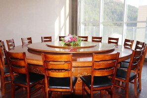 Una mesa de madera redonda rodeada de sillas, con un arreglo floral sobre la mesa.
