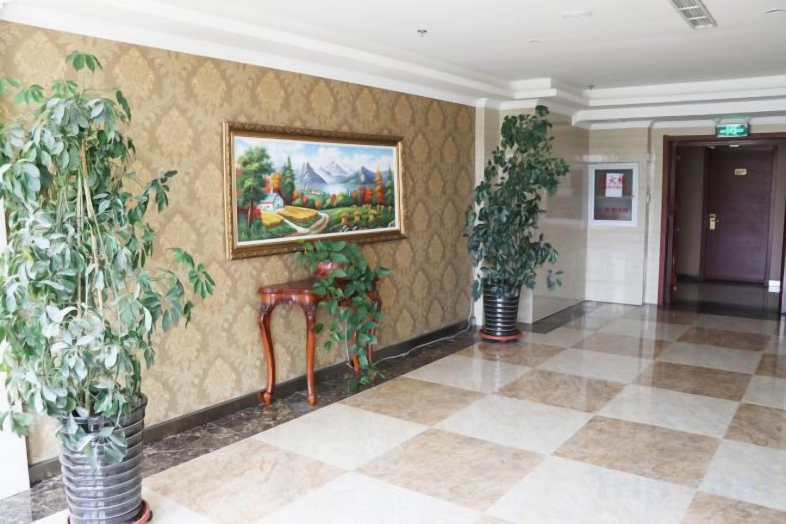 Um hall de hotel com piso xadrez, um quadro na parede e plantas em vasos.