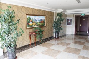 Un vestíbulo de hotel con piso a cuadros, un cuadro en la pared y plantas en macetas.