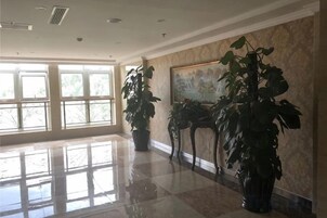 Un vestíbulo espacioso con amplias ventanas, piso pulido y varias plantas en macetas.