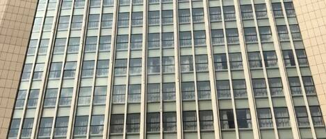 A high-rise building with a grid of windows and a beige facade.