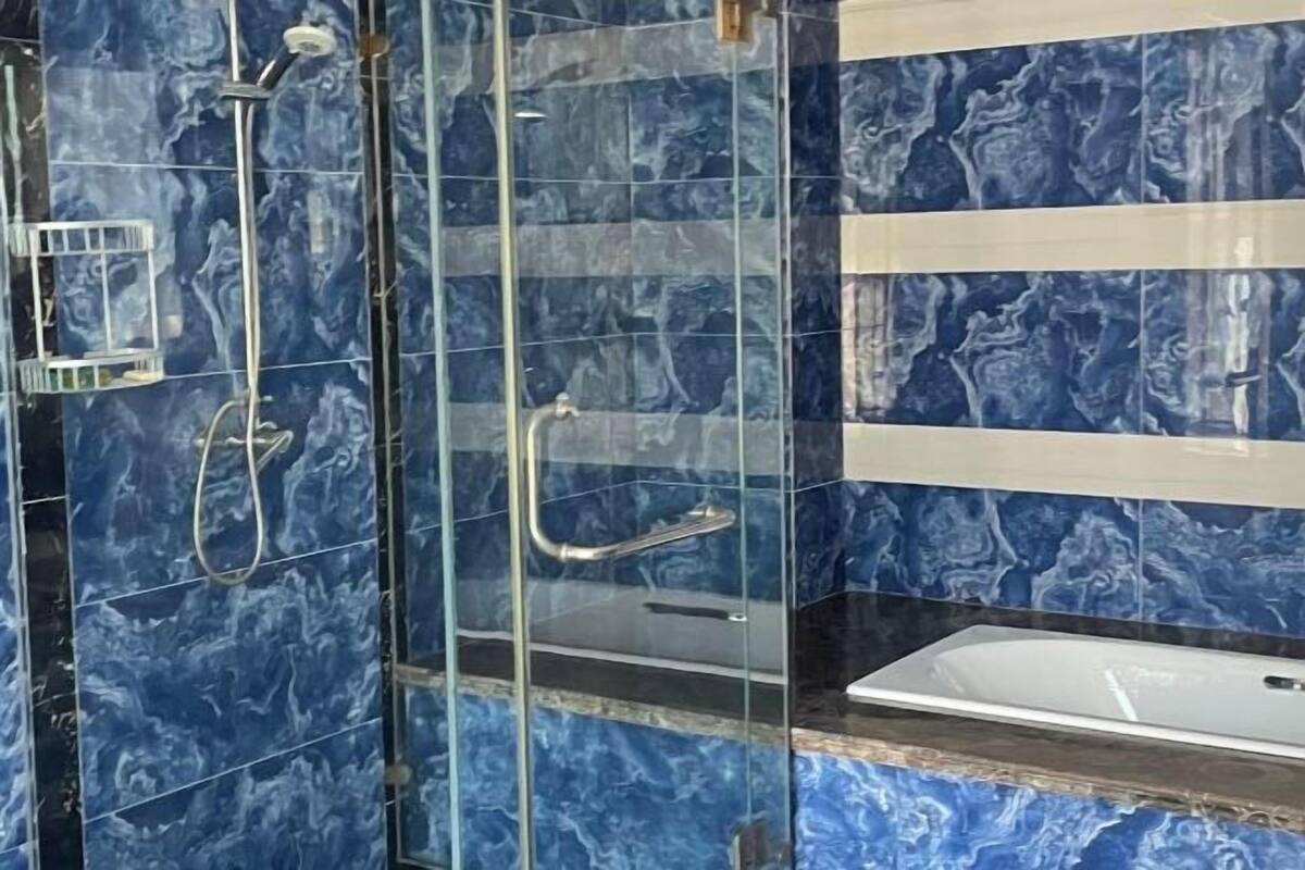 Ein Badezimmer mit blauen Marmorfliesen, einer Duschkabine aus Glas und einem weißen Waschbecken.