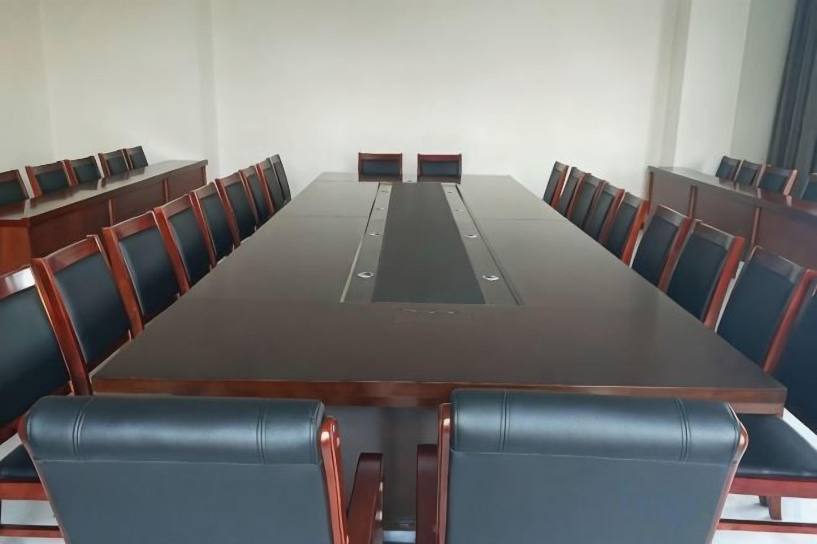 Uma sala de conferências com uma mesa comprida e cadeiras, um projetor e uma lousa.
