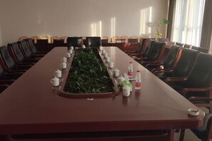 Ein Konferenzraum mit einem langen Tisch, Stühlen und einer Pflanze.