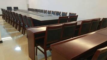 Un salón de conferencias con una larga mesa y sillas, un proyector y una pizarra.