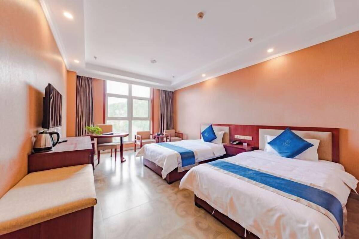 Ein Hotelzimmer mit zwei Betten, einem Schreibtisch, einem Sessel und einer Couch.