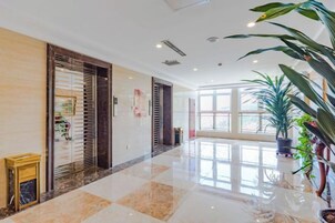 Un vestíbulo de hotel con piso de mármol pulido, ventanas amplias y plantas en macetas.