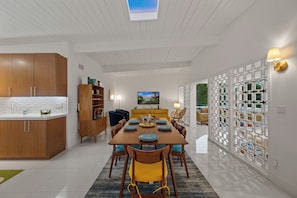 Una cocina moderna con armarios de madera, un comedor con mesa para cuatro personas y vistas a una piscina por la ventana.