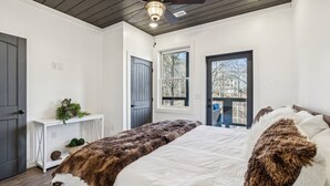 Ein Schlafzimmer mit einem großen Bett, einem Schreibtisch und zwei Fenstern.