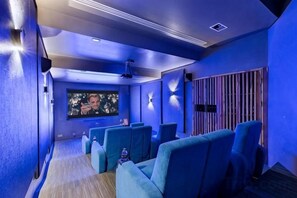 A home theater room with blue walls, a large screen, and multiple seating areas. - Villa Skyfall : Spectacular 8 Bedroom Pool Villa with Private Cinema (Koh Samui)