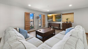 A modern living room with a sofa set, a coffee table, a cabinet, and a large painting on the wall.