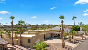 A residential property with a beige exterior, a patio area, and a view of neighboring houses.