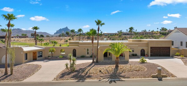 A residential area with modern houses, palm trees, and a mountainous backdrop.