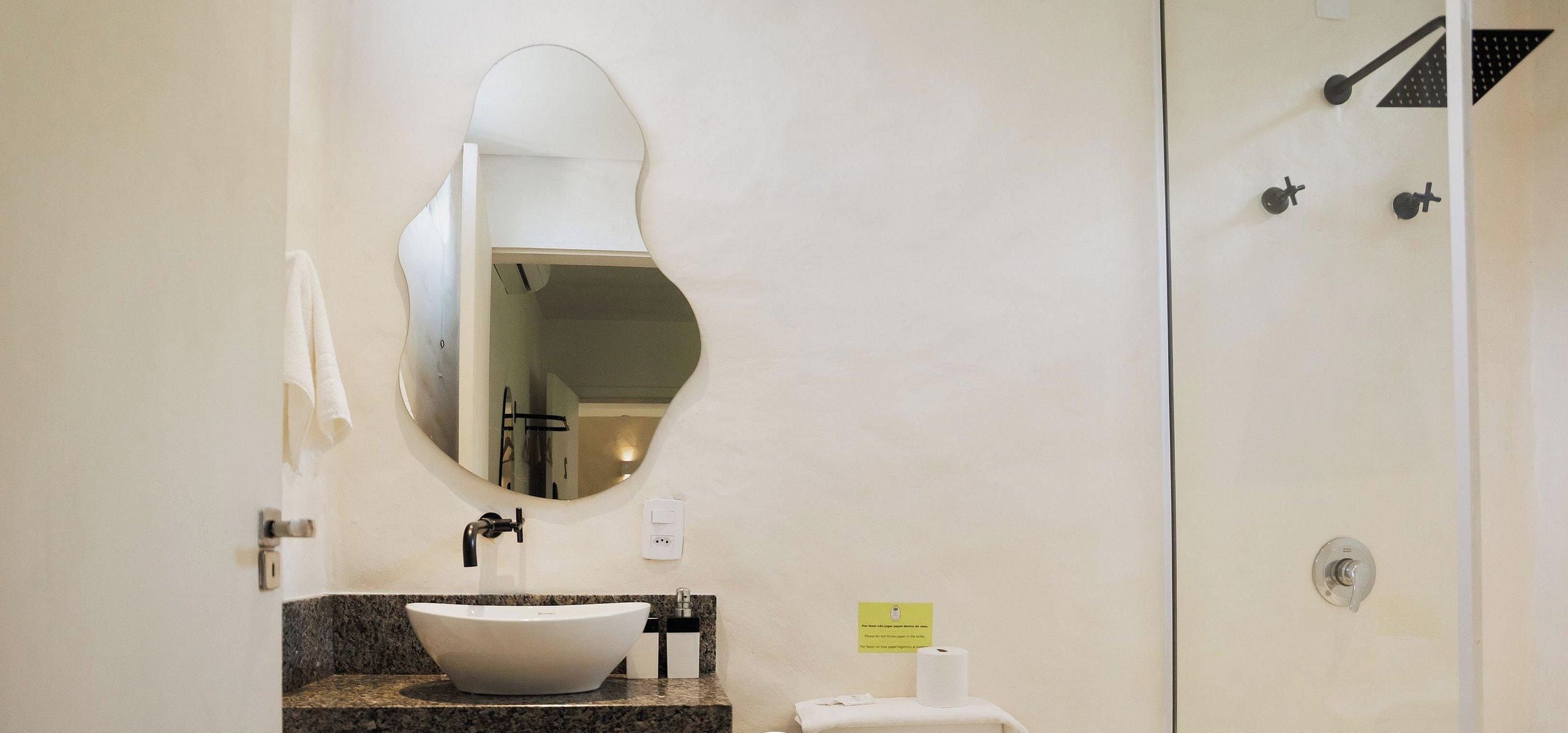 A bathroom with a white sink, a mirror, a towel, and a shower.
