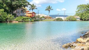 A clear waterfront with buildings, palm trees, and a calm river. - Quinta da Margem (Florianópolis)
