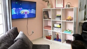 A living room with a TV, a sofa, a bookshelf, and a child. - Quinta da Margem (Florianópolis)