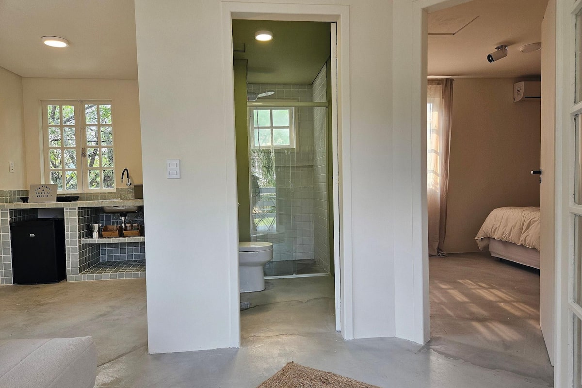 A spacious kitchen with a large window, a separate dining area, and a bathroom with a shower and toilet.