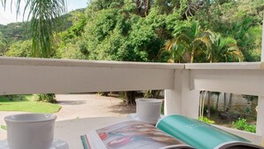A balcony with a table, two cups, and an open magazine. - Quinta da Margem (Florianópolis)