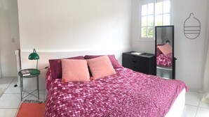 A bedroom with a bed, pillows, a nightstand, a lamp, a mirror, and a window. - Quinta da Margem (Florianópolis)