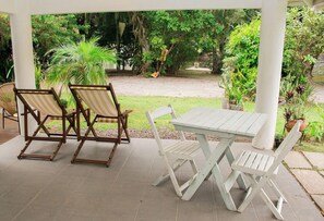 A covered outdoor seating area with a table and chairs, surrounded by greenery and a gravel path. - Quinta da Margem (Florianópolis)