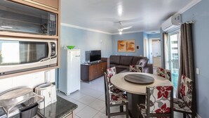 A compact living space with a kitchen area, dining table, and a sofa. - 150m do Mar! Cobertura Duplex com Piscina Privada (Bombinhas)