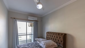 A bedroom with a bed, a ceiling fan, and a window with curtains. - 150m do Mar! Cobertura Duplex com Piscina Privada (Bombinhas)