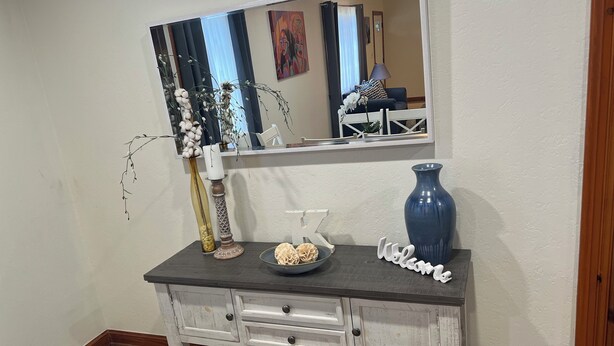 Une commode blanche avec des tiroirs, un vase bleu et une pancarte « Bienvenue ».