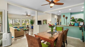 A spacious living area with a dining table, chairs, and a ceiling fan. There is a kitchen area with a refrigerator and a countertop. - 5 Beds Downstairs Corner Unit with AC, 3 Pools, 6 minutes to Beaches, Beach Cart (Koloa)