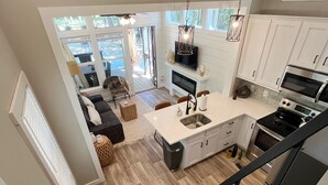 A modern kitchen with white cabinetry, a central island, and a built-in oven. - Eagle’s Nest Tiny House: Cozy Escape w/ Porch, Patio + Fire Pit (Tracy)