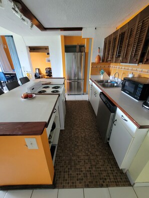 A compact kitchen with a stainless steel refrigerator, a microwave, and a stove. - Sea Turtle Condo with Loaded Amenities (Christiansted)