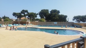 A swimming pool with lounge chairs and a sandy area.