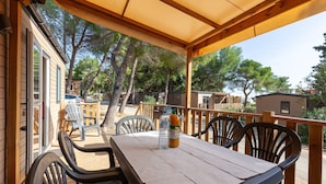 A covered outdoor seating area with a table, chairs, and a bottle of water.