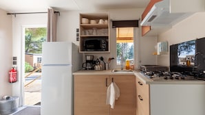 A compact kitchen with a refrigerator, microwave, stove, and wooden cabinets.
