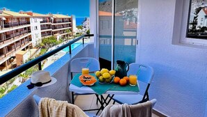 A balcony with a table set for breakfast, a view of the sea, and a building complex in the background. - Vacation Apartment 'Relaxing Los Cristianos' with Sea View, Wi-Fi and Air Conditioning (Los Cristianos)