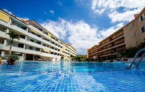 Une piscine dont le fond est recouvert de carrelage, entourée d’immeubles à plusieurs étages dotés de balcons.