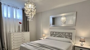A bedroom with a bed, nightstands, a dresser, a chandelier, and a mirror. - Vacation Apartment 'Relaxing Los Cristianos' with Sea View, Wi-Fi and Air Conditioning (Los Cristianos)