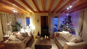 Ein gemütliches Wohnzimmer mit Kamin, zwei Sofas, einem Couchtisch und einem Weihnachtsbaum.