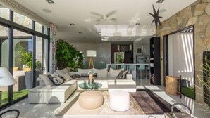 Una sala moderna con un sofá, reposapiés y una mesa de centro de vidrio.