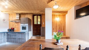 A wooden interior with a kitchen, dining area, and a TV mounted on the wall.