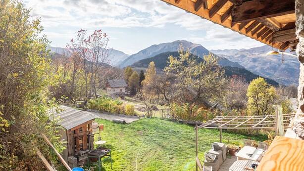 A rustic wooden structure with a view of mountains and a garden.
