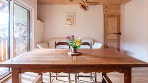 A wooden dining table with chairs, a chandelier, a wall-mounted picture, and a door.