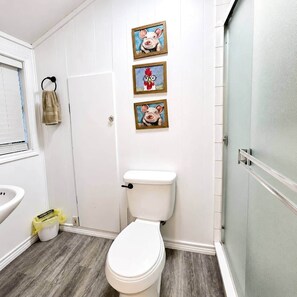 Un baño con inodoro blanco, suelo de madera y dos cuadros con imágenes de animales en la pared.