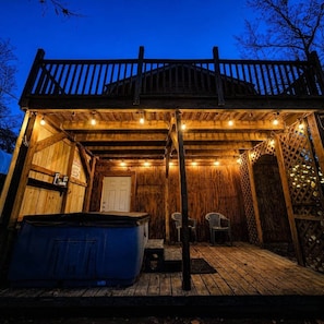 Une cabane en bois dotée d’un porche couvert, d’un jacuzzi et d’une porte.