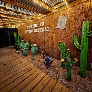 Un mur en bois sur lequel est affiché un panneau indiquant « BIENVENUE À RUSTIC RETREAT », ainsi qu’une terrasse en bois.