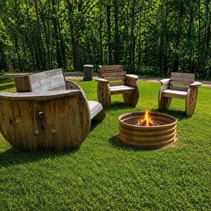 Un foyer extérieur avec des sièges en bois et une zone herbeuse.