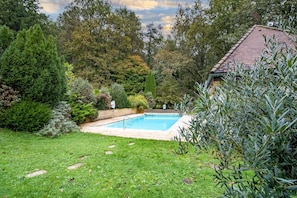 A backyard with a swimming pool, surrounded by various trees and shrubs. - Scarabée Guest Room – Elegance and Serenity with Shared Pool and Air Conditioning (Sarlat-la-Canéda)